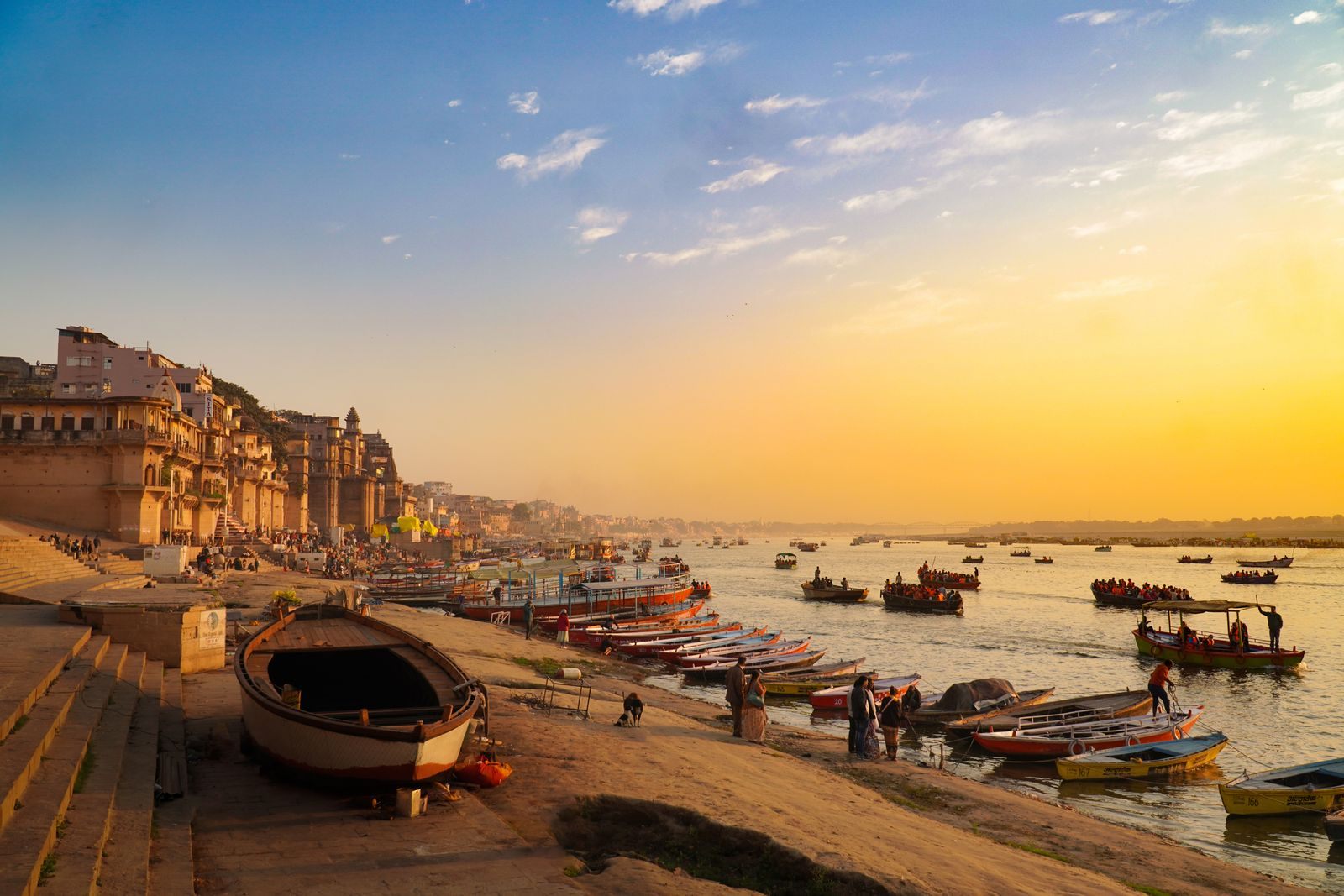 Boats lining the Ganges below the ghats of Varanasi in golden-hour light, the setting of every Ganges river cruise to Varanasi